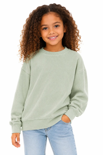Young girl wearing a light green sweater and blue jeans on a white background