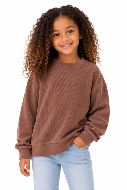 Young girl wearing a brown sweatshirt and light blue jeans on a white background