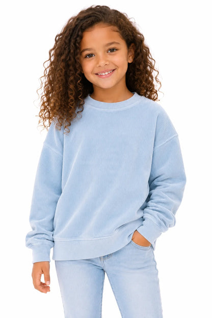 Child wearing a light blue sweatshirt and pants on a white background